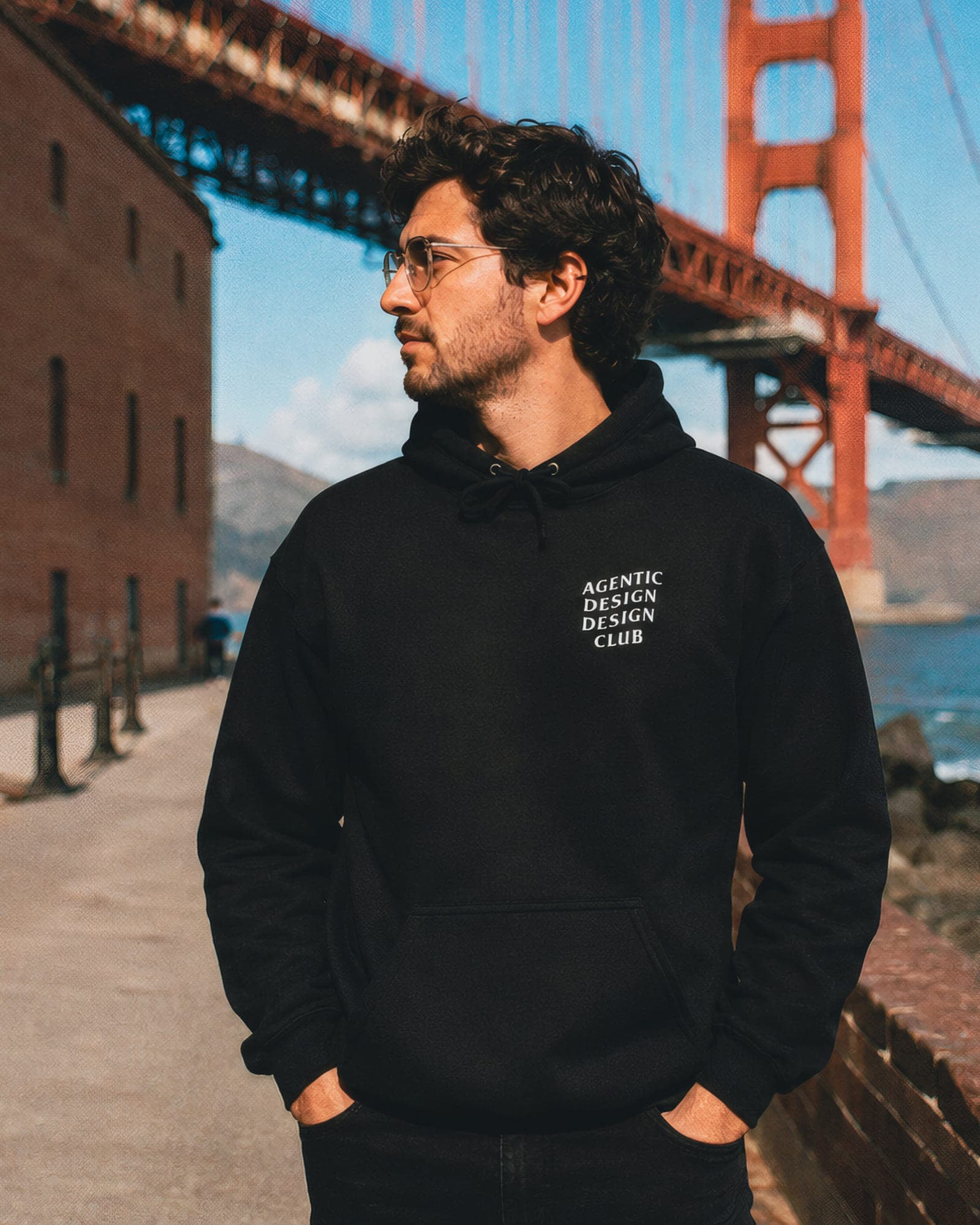 A designer in the black Agentic Design Design Club hoodie by the Golden Gate Bridge